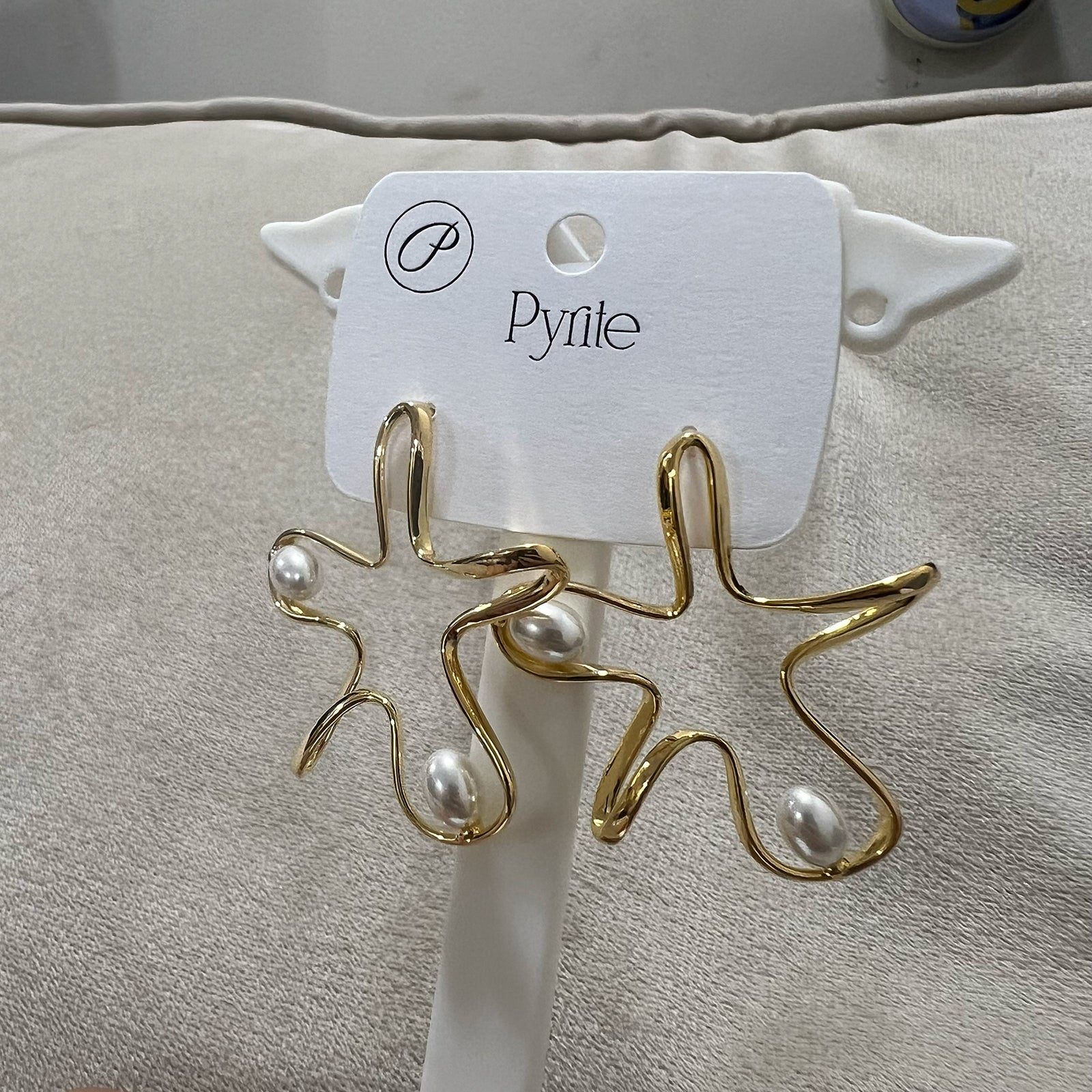 Side view of contemporary organic gold star statement earrings featuring inset white pearls