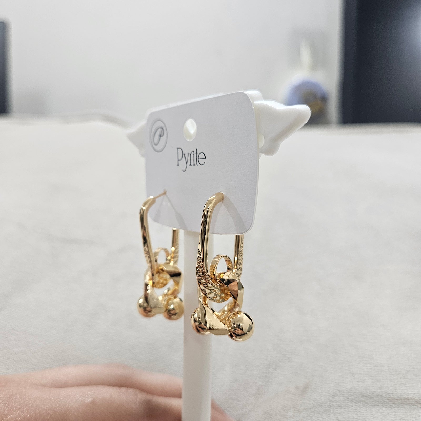 Angled view of anti-tarnish stainless steel abstract earrings showing the polished spheres and geometric link design