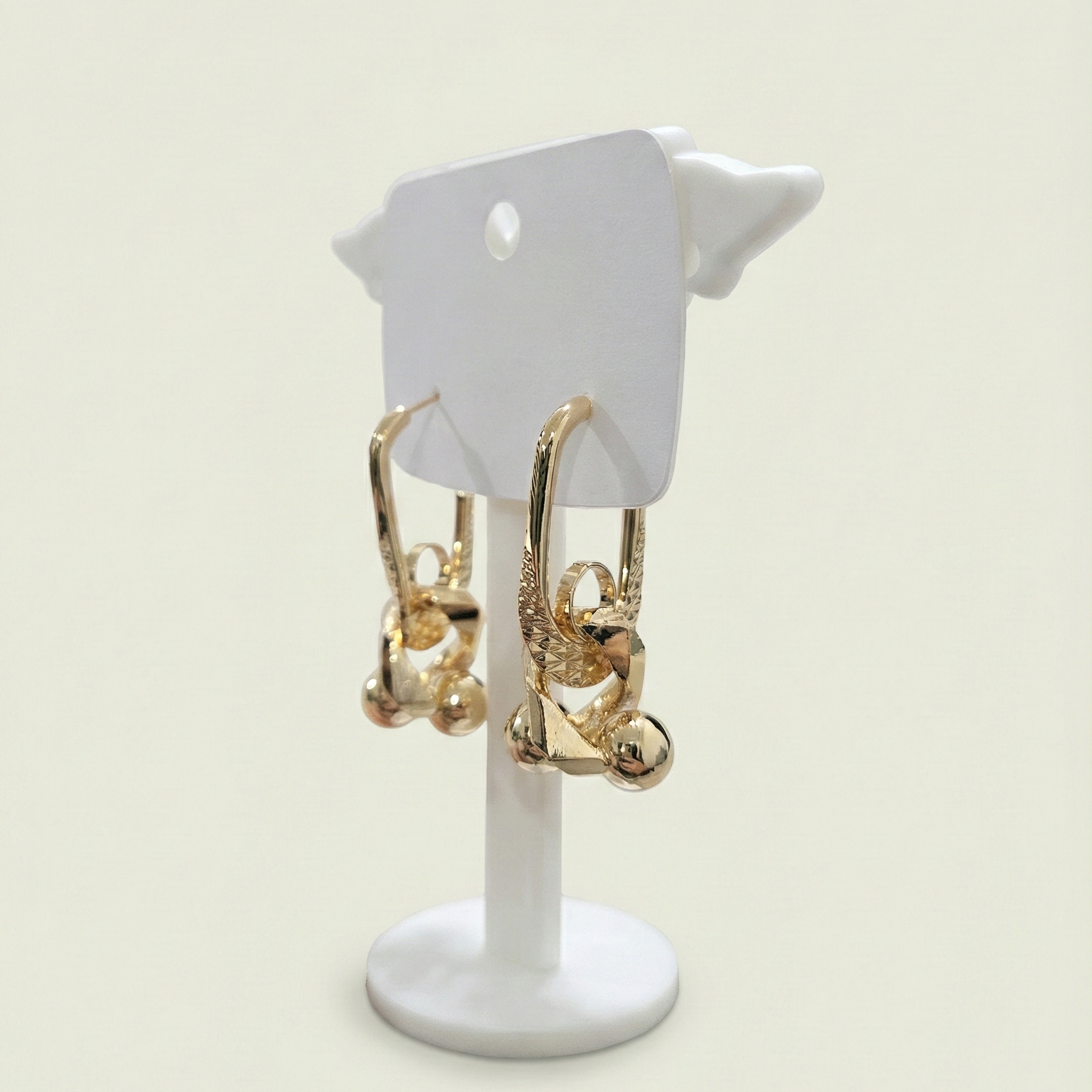 Frontal view of gold plated sculptural link earrings featuring a unique textured finish on a white jewellery stand