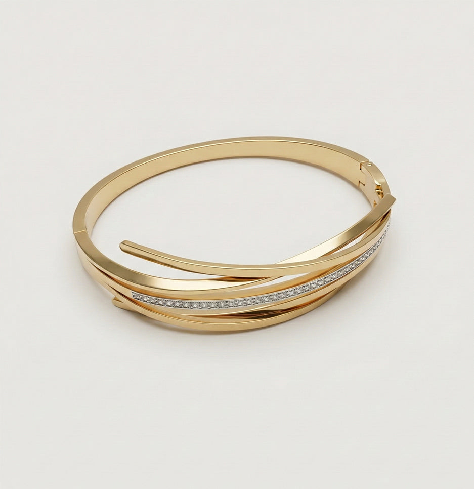 Top down view of a multi-layer gold-tone bangle featuring a paved crystal strand against a neutral studio background