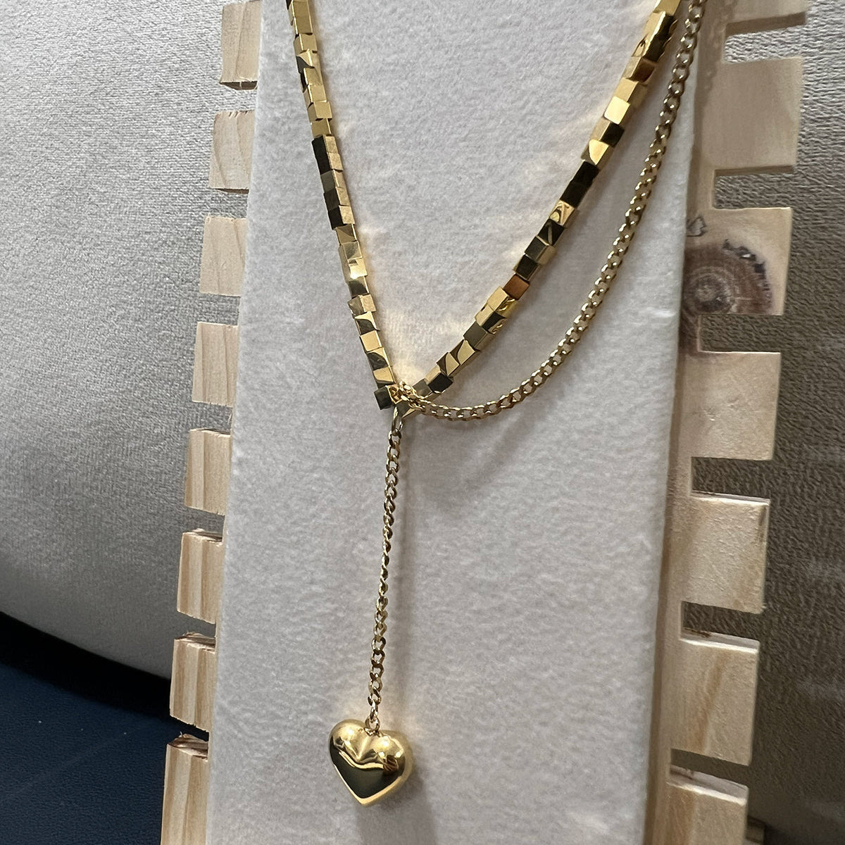 Side view of a tarnish resistant stainless steel heart drop necklace showcasing the geometric block chain detail.