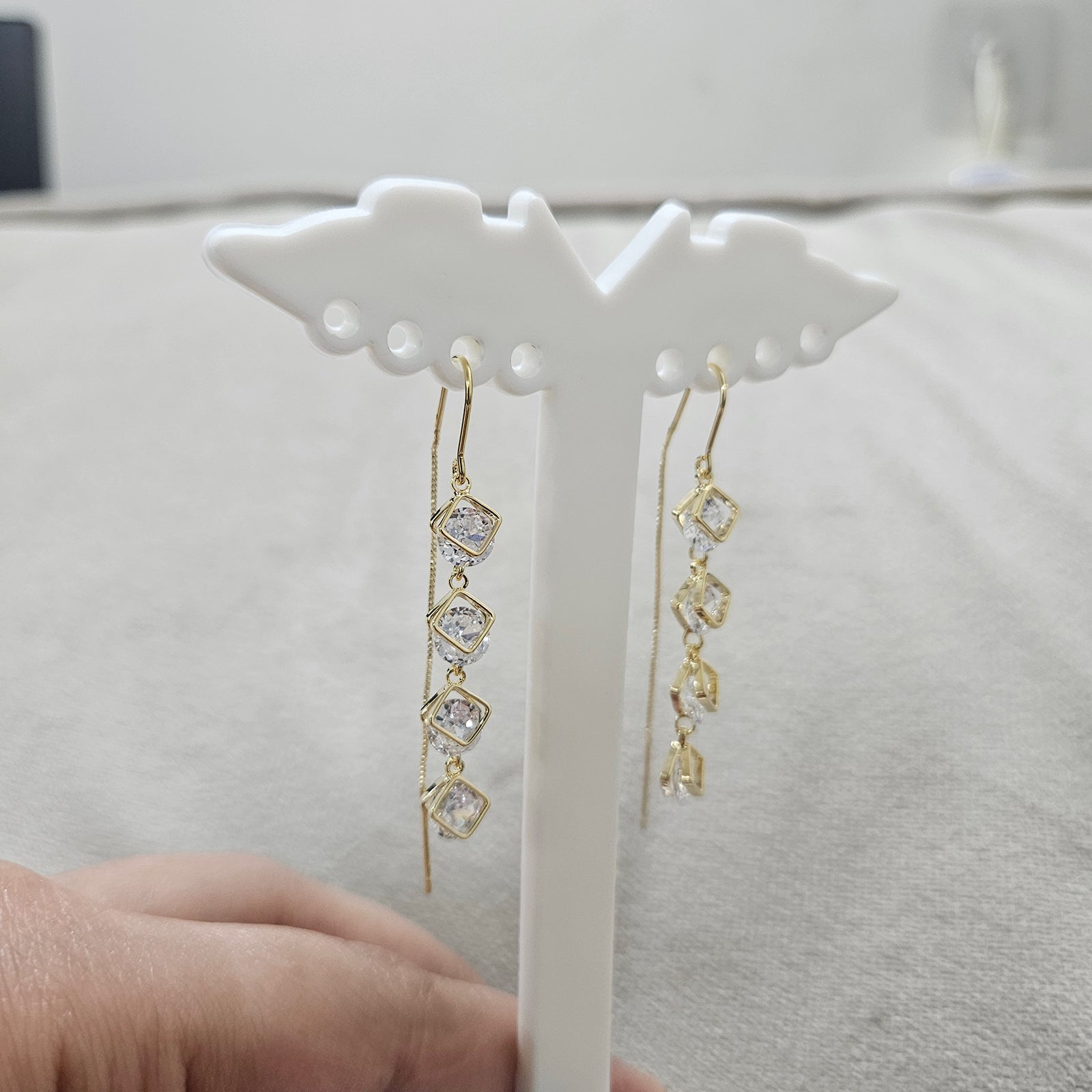 Detailed side view of anti-tarnish gold plated linear earrings featuring shimmering geometric square crystals