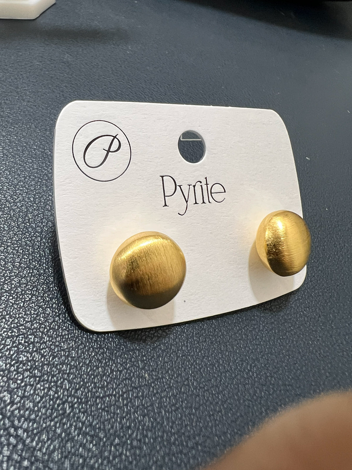 Angled view of minimalist half-ball earrings in gold-plated stainless steel with a contemporary satin texture