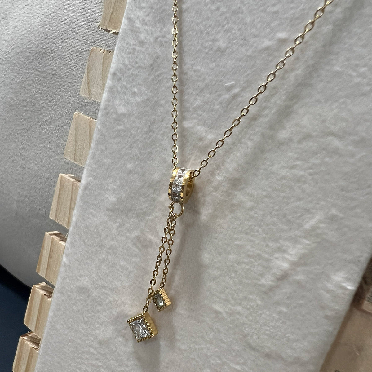 Close-up of a tarnish resistant gold Y-necklace with shimmering square crystal charms and a delicate cable chain