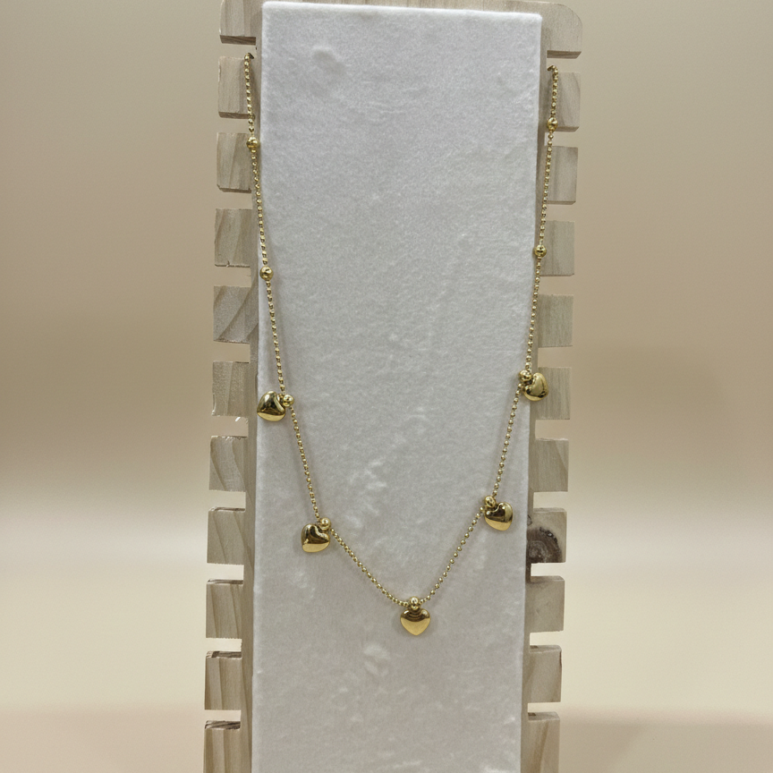 Anti-tarnish heart charm necklace in gold-toned stainless steel shown on a professional wooden jewelry stand.