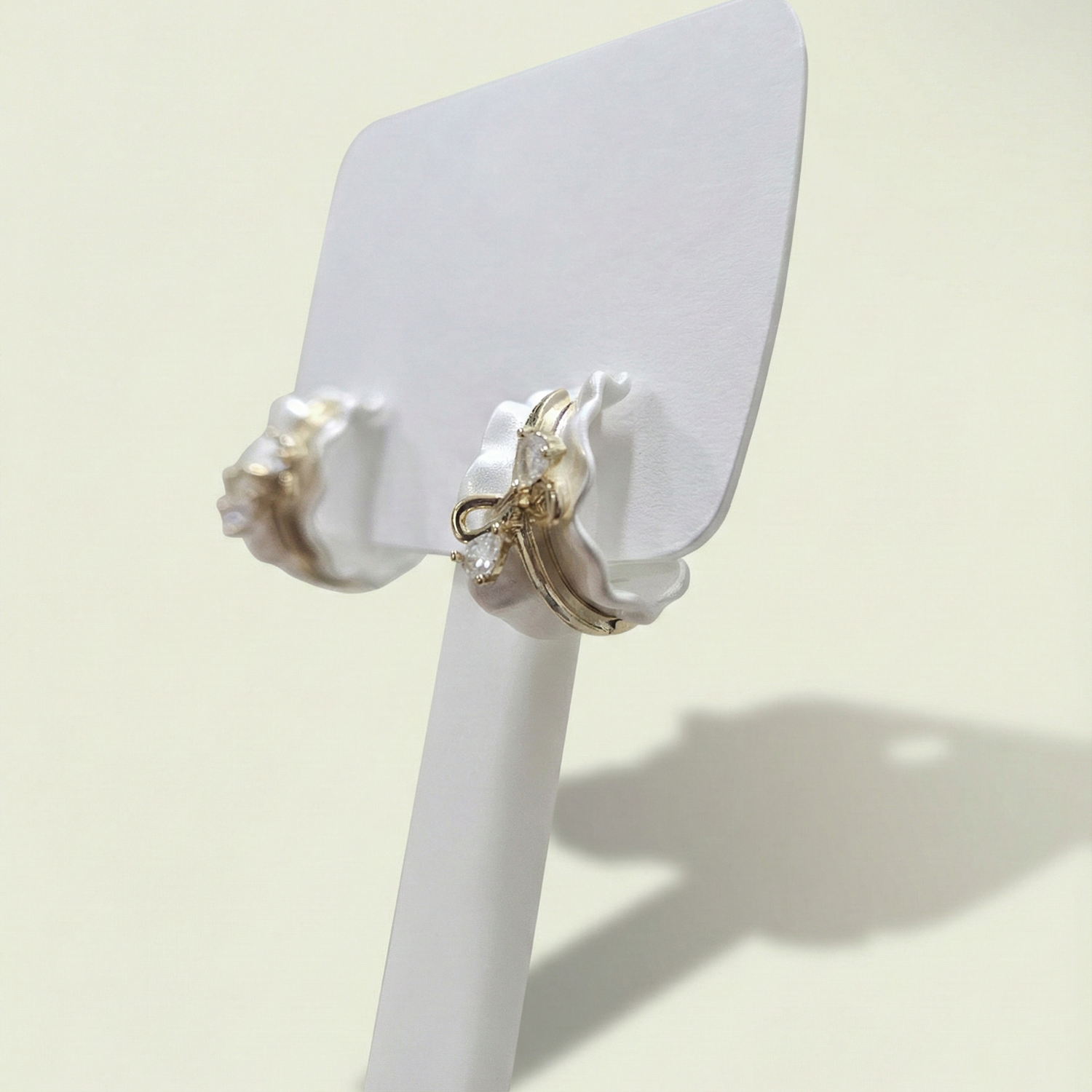 Pair of earrings on a white stand against a light background