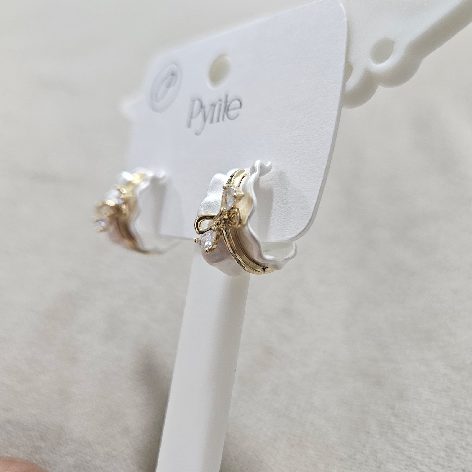 Gold hoop earrings on a zwelzy branded card against a beige background
