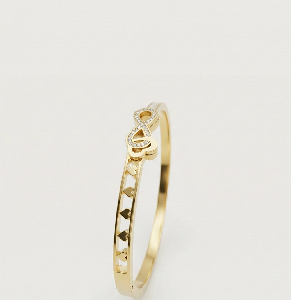 Side profile view of an anti-tarnish stainless steel infinity bangle showing the intricate heart pattern design