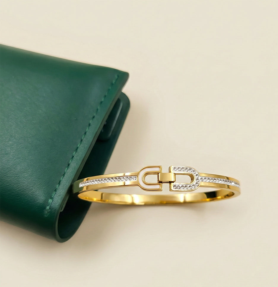 Side view of an anti-tarnish gold plated stainless steel bracelet resting on a green leather pouch