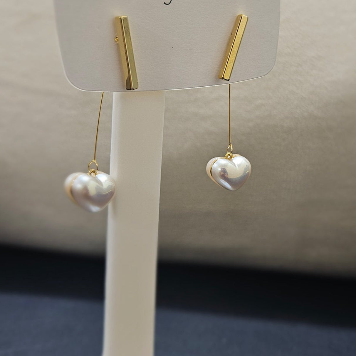 Angled view of anti-tarnish gold plated earrings showing the sleek stainless steel bar and lustrous heart pearl drop