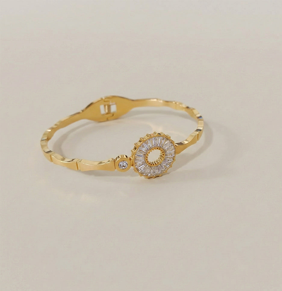 Close up angled shot of a luxury gold plated fashion bracelet for women with a shimmering halo design