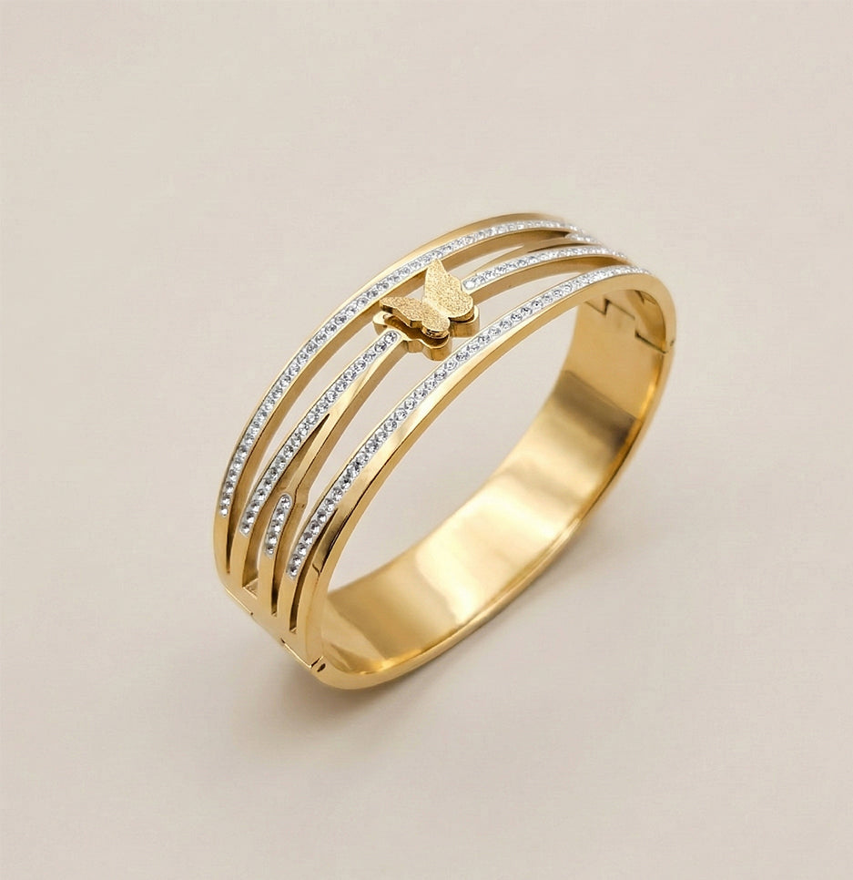 Angled shot of a polished gold stainless steel butterfly cuff showing the intricate pavé crystal bands