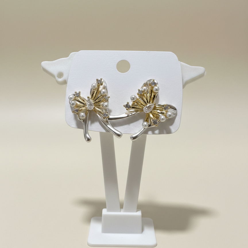 Dual-tone butterfly earrings with white pearl accents and a teardrop center stone on a white display stand.