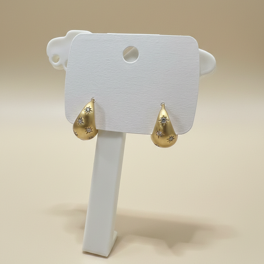 ront view of gold plated teardrop earrings featuring celestial star engravings and clear shimmering stones
