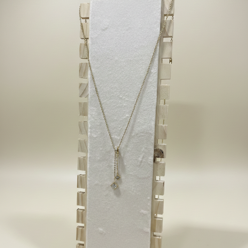Elegant gold plated lariat necklace featuring a crystal barrel junction and square crystal pendants on a white display.