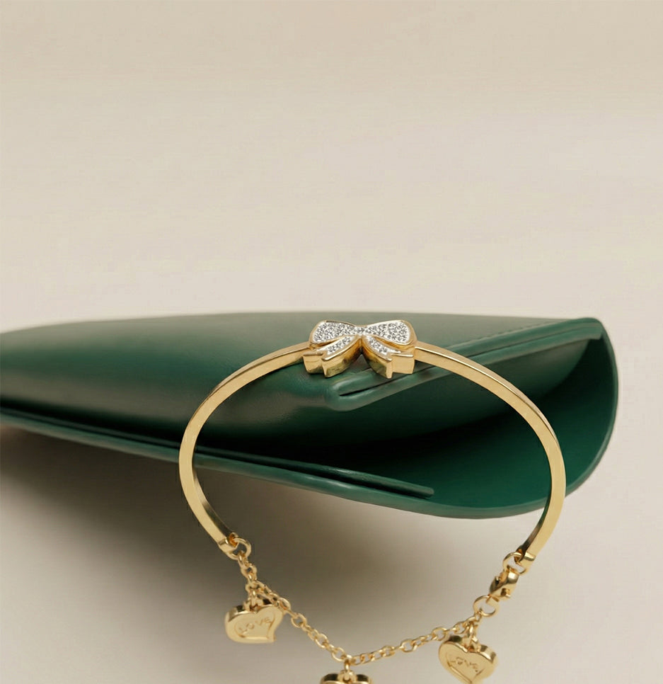 Close-up of a gold plated stainless steel bracelet featuring a sparkling crystal-encrusted bow centerpiece