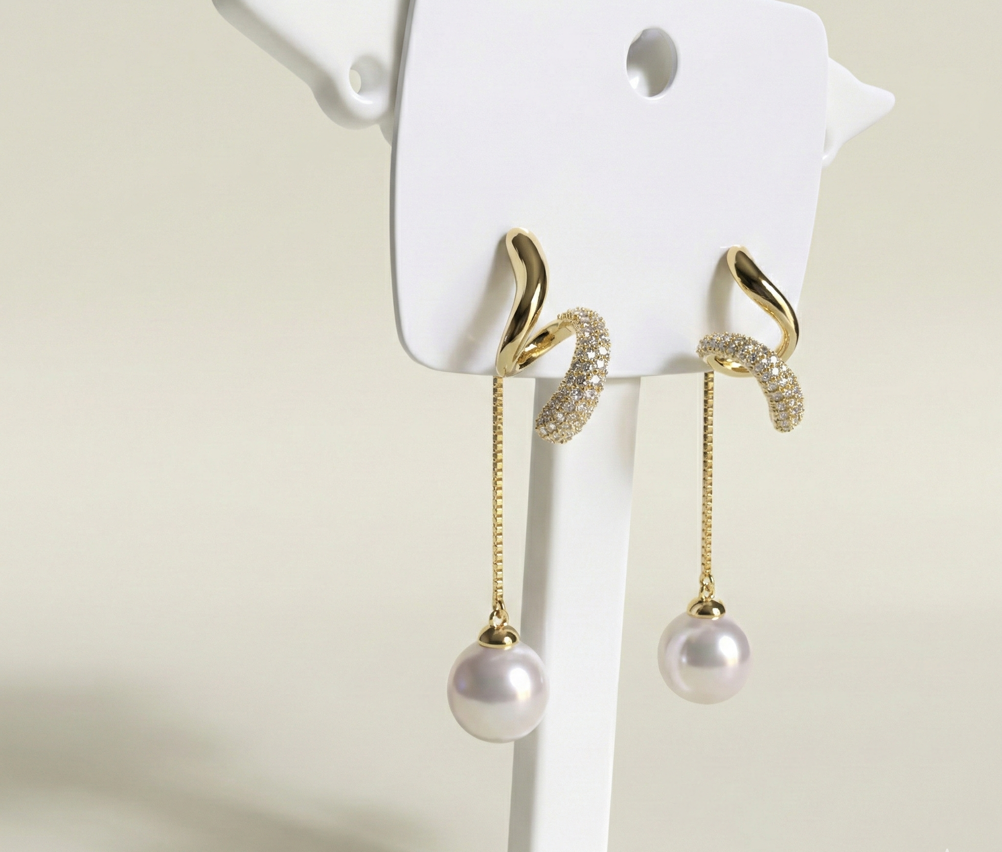 Gold earrings with pearl drops on a white background