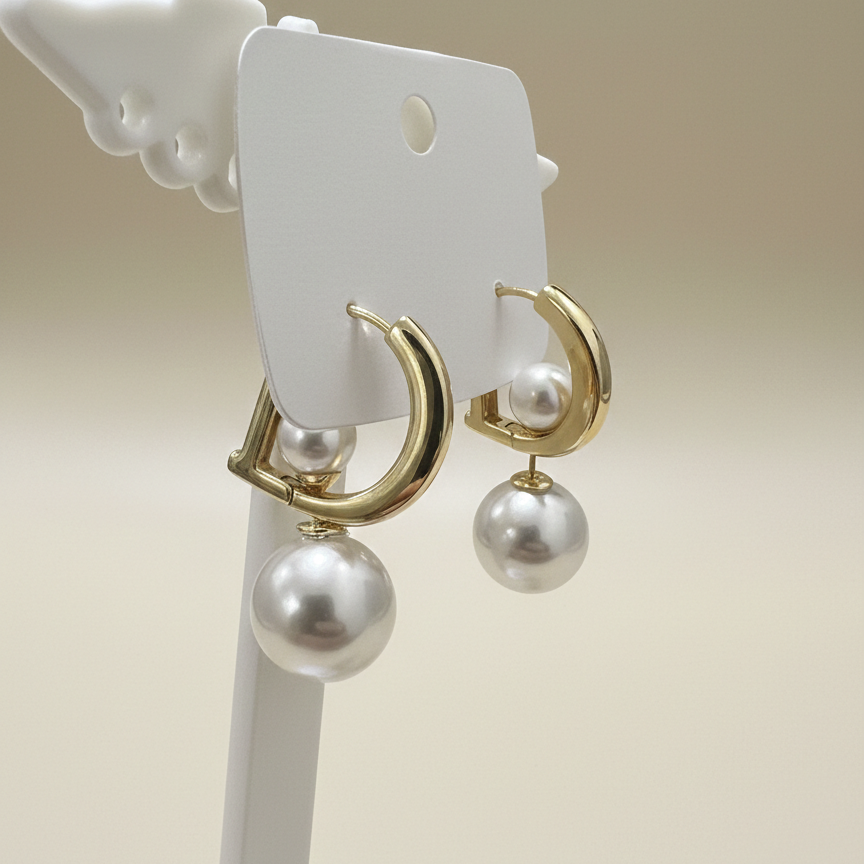 Flat lay view of gold plated D initial earrings featuring a detachable double pearl backing on a textured surface.