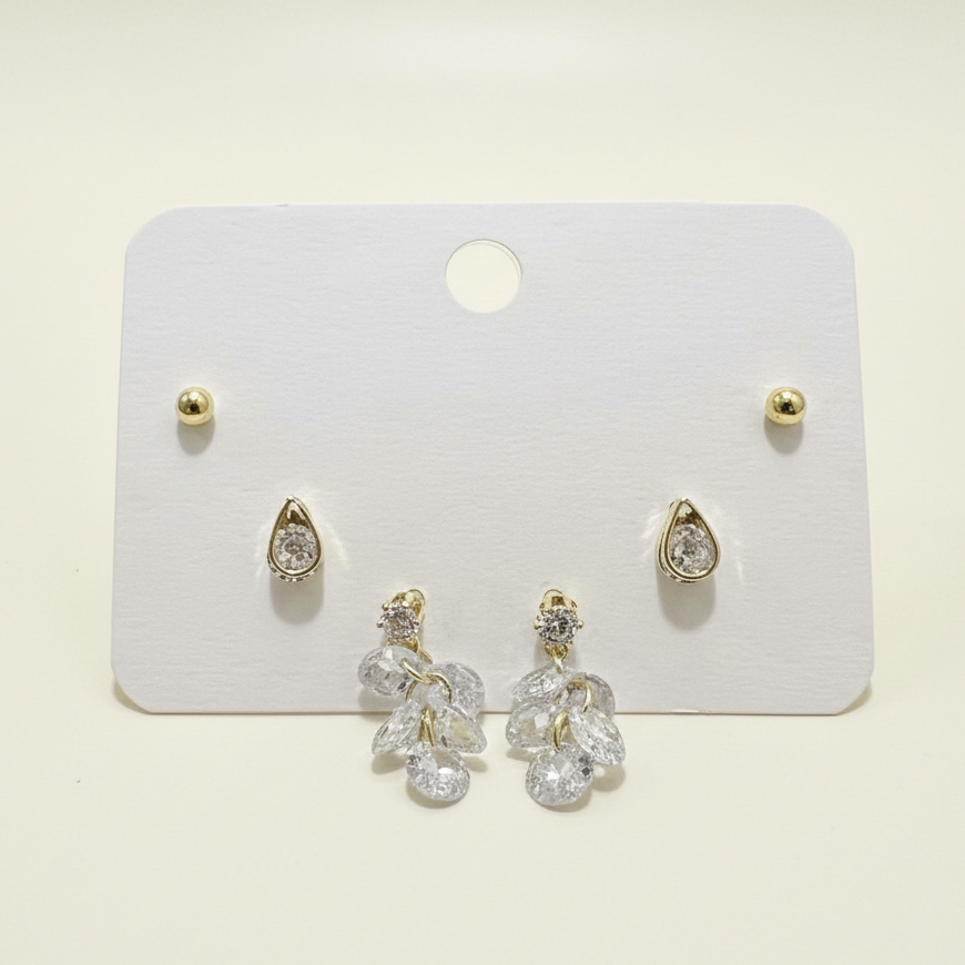 A three-pair set of gold plated anti-tarnish earrings featuring crystal studs and floral drops on a white display card.
