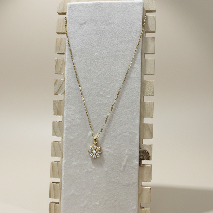 Elegant gold plated floral necklace with a pearl center showcased on a professional wooden vertical jewelry stand.