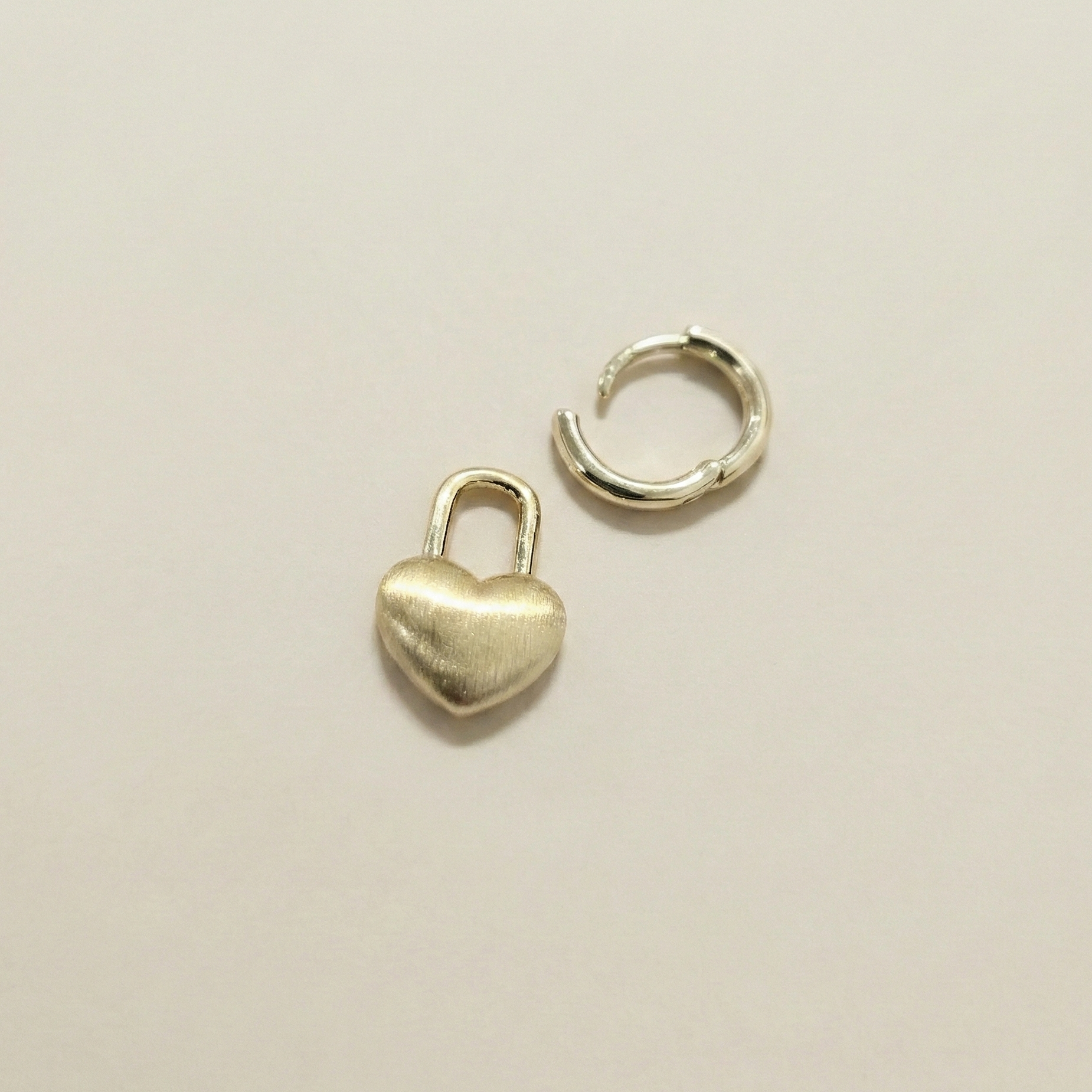Pair of gold heart padlock dangle earrings displayed on a white professional jewelry stand for a premium look