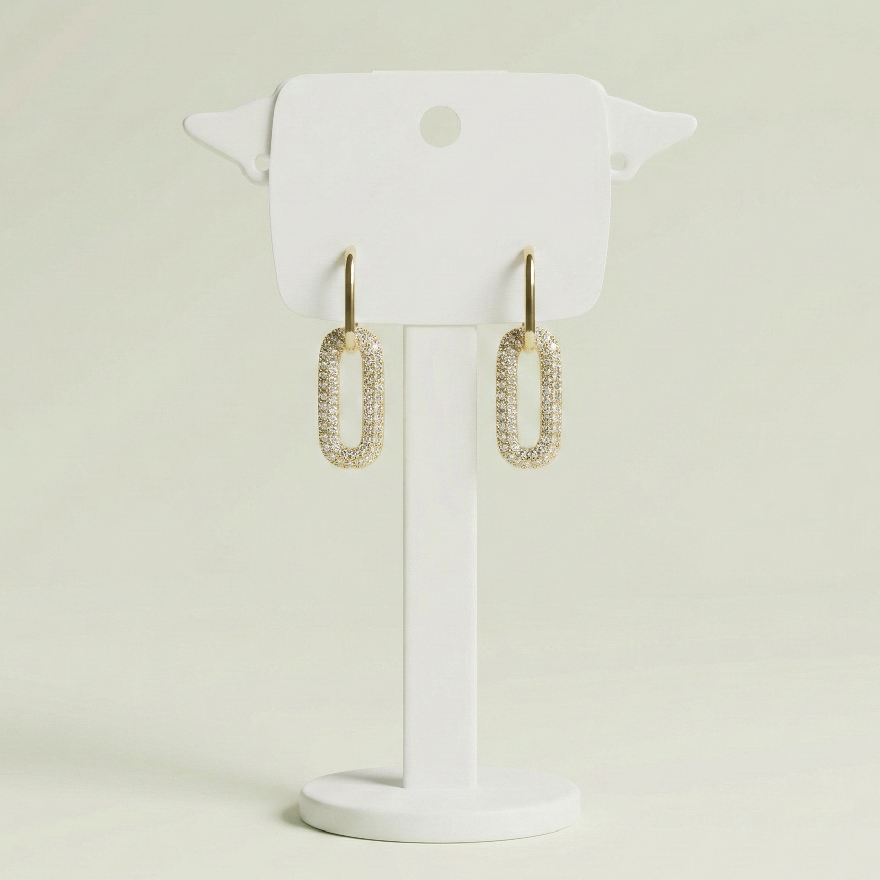 Pair of gold plated link earrings featuring one polished and one pavé crystal link on a white display card