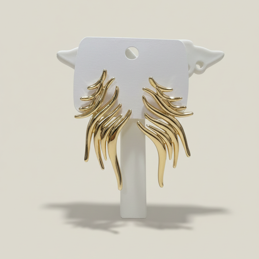 A pair of abstract flame-shaped gold plated earrings displayed on a white branded card