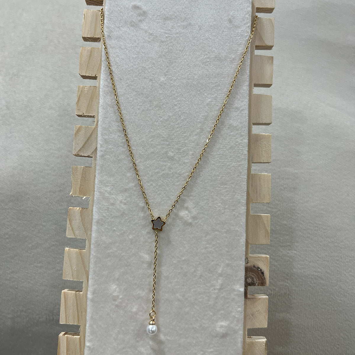 Anti-tarnish gold Y-necklace with a celestial star and pearl pendant shown on a professional wooden jewelry stand