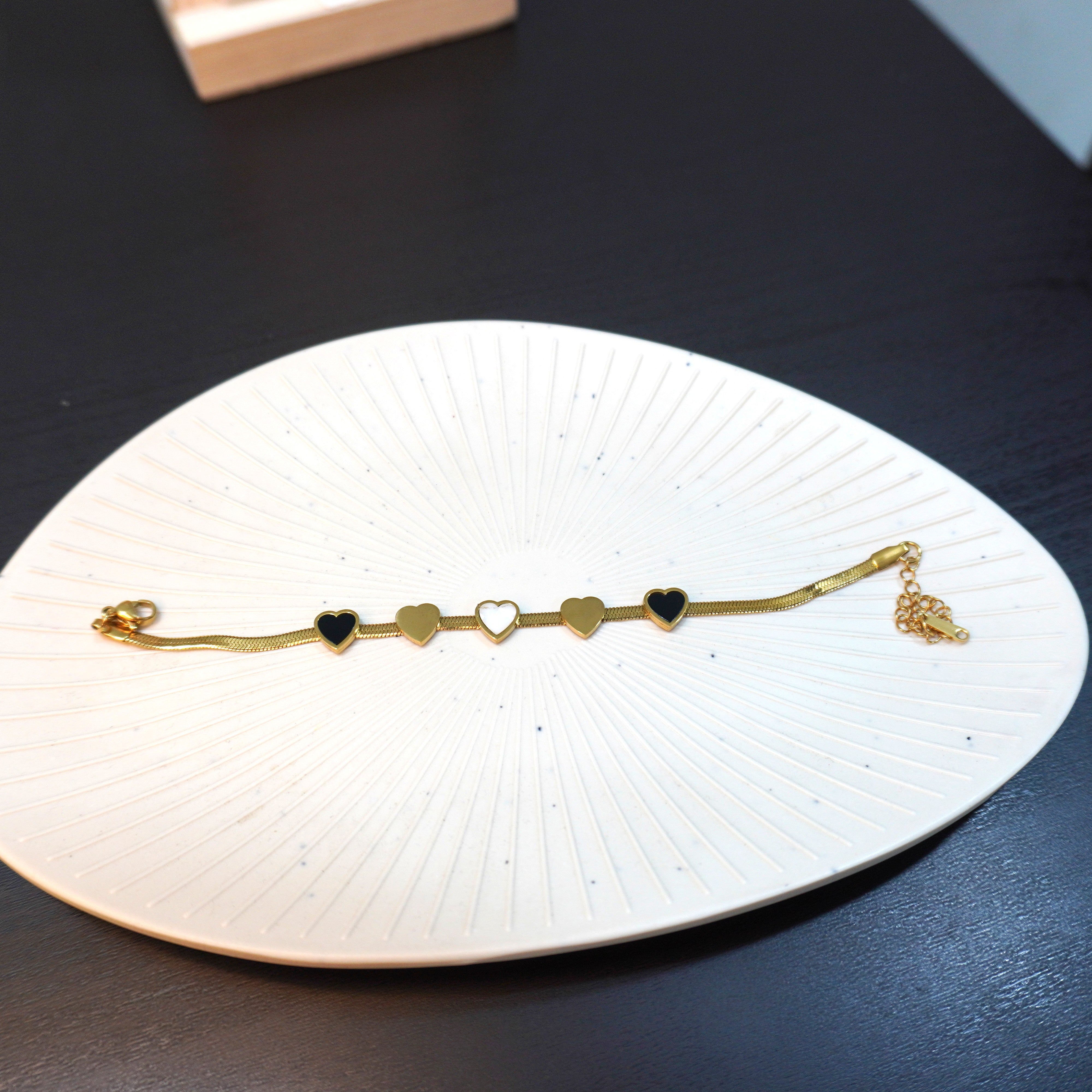 Gold bracelet with heart charms on a white dish