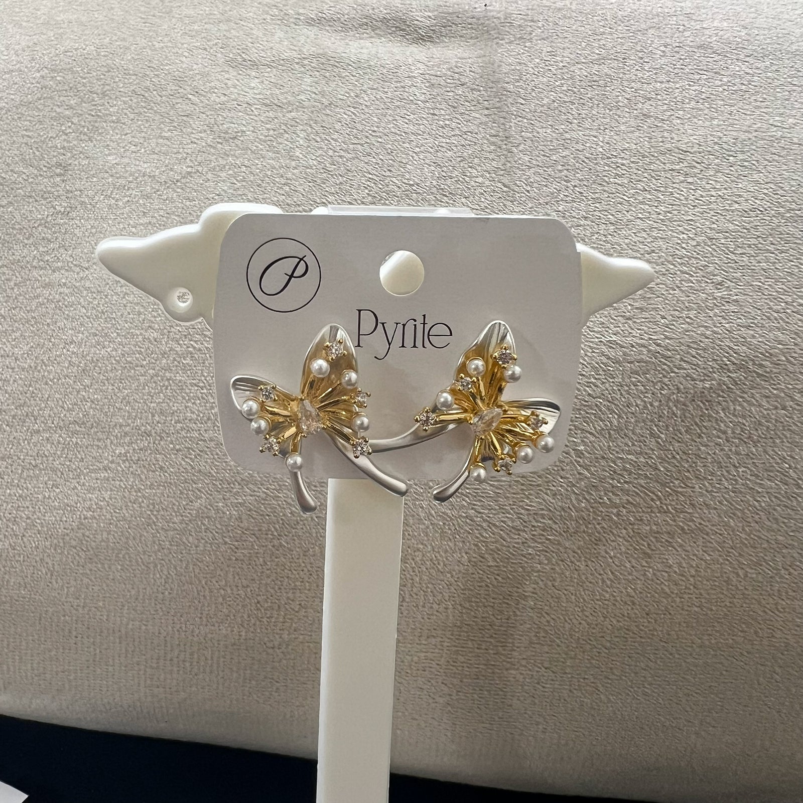 Close-up view of gold plated butterfly stud earrings showing intricate wing textures and pearl embellishments