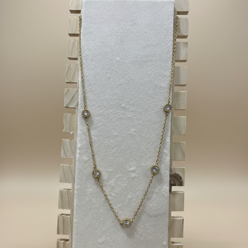 Professional studio view of a minimalist anti-tarnish station necklace with sparkling bezel-set stones on a display.