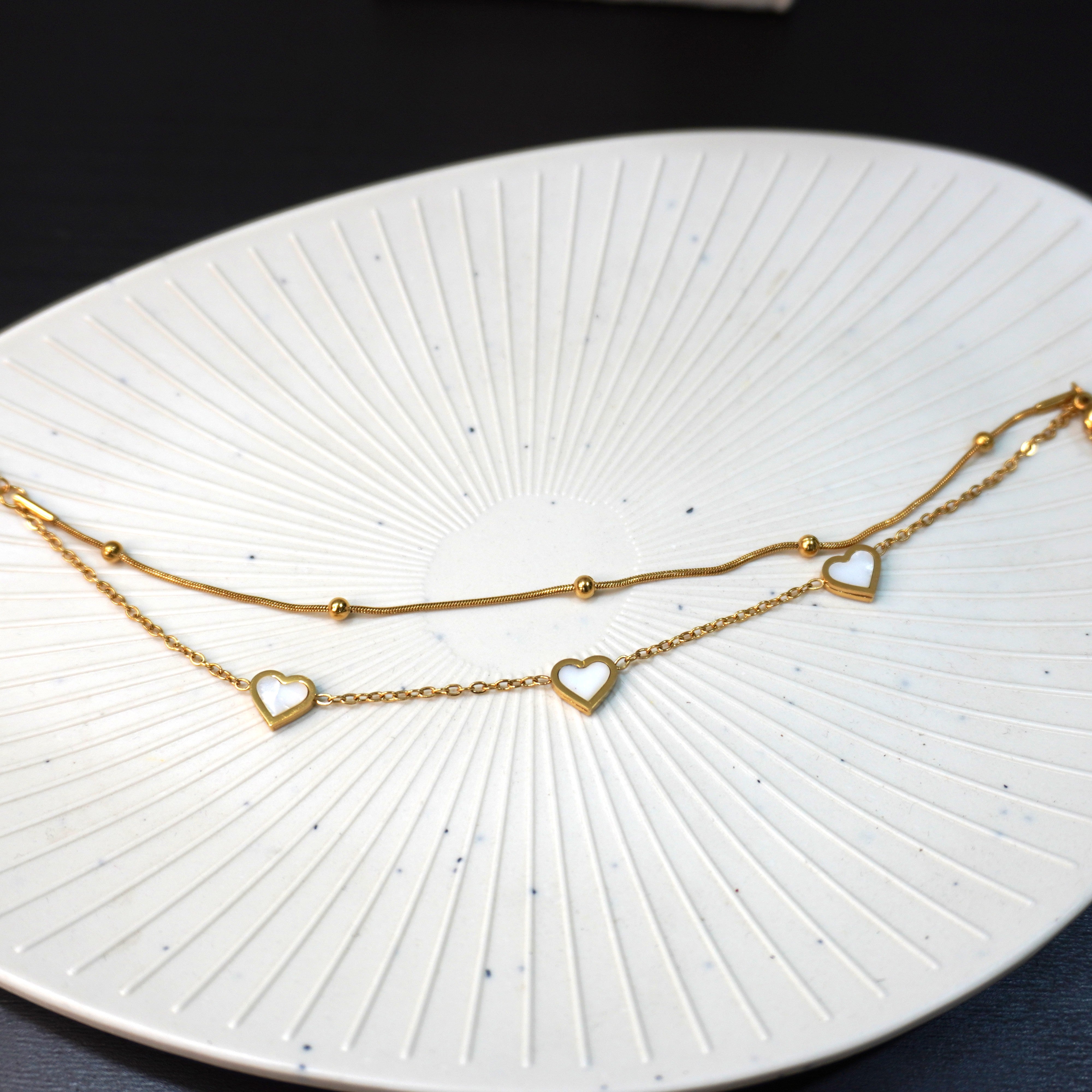 Gold heart-shaped necklace on a white textured plate