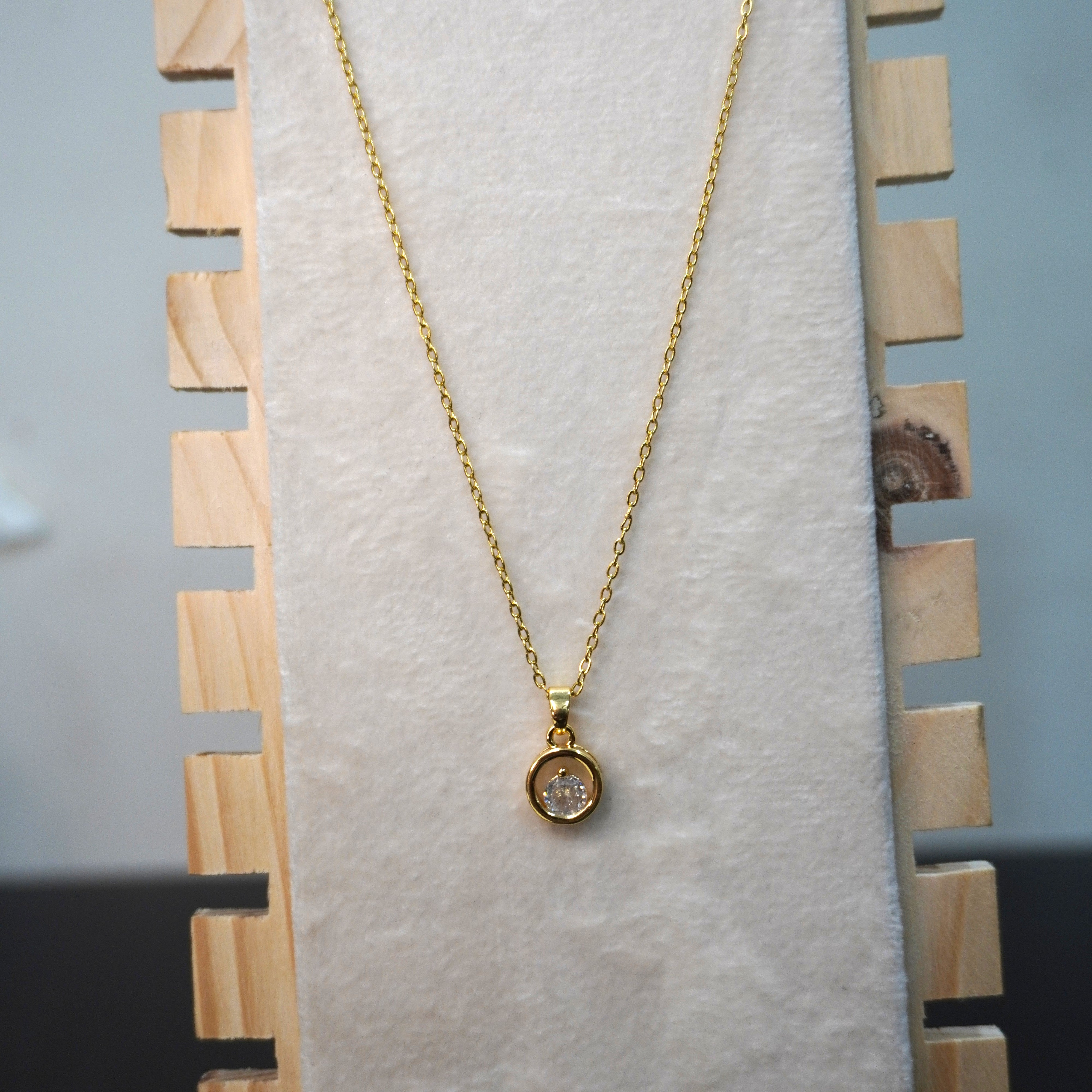 Gold necklace with a pendant on a wooden stand