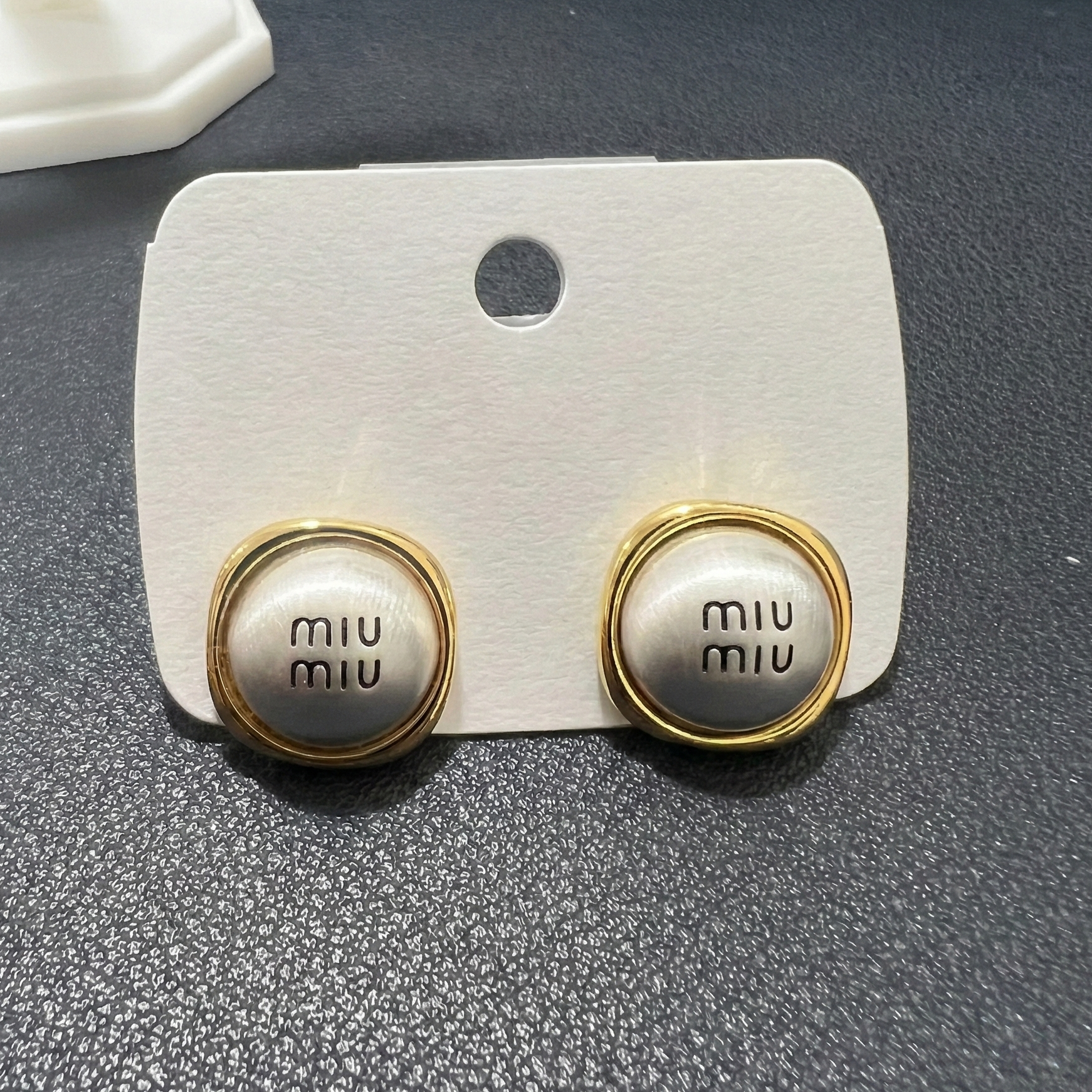 Angled shot of designer inspired gold and silver tone stud earrings featuring a modern circular disc design