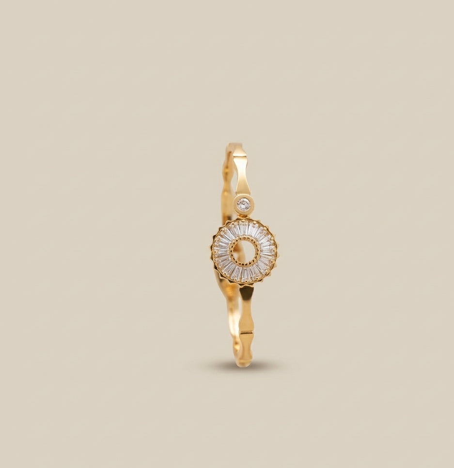 Top down view of a gold plated stainless steel bracelet featuring a circular sunburst crystal centerpiece