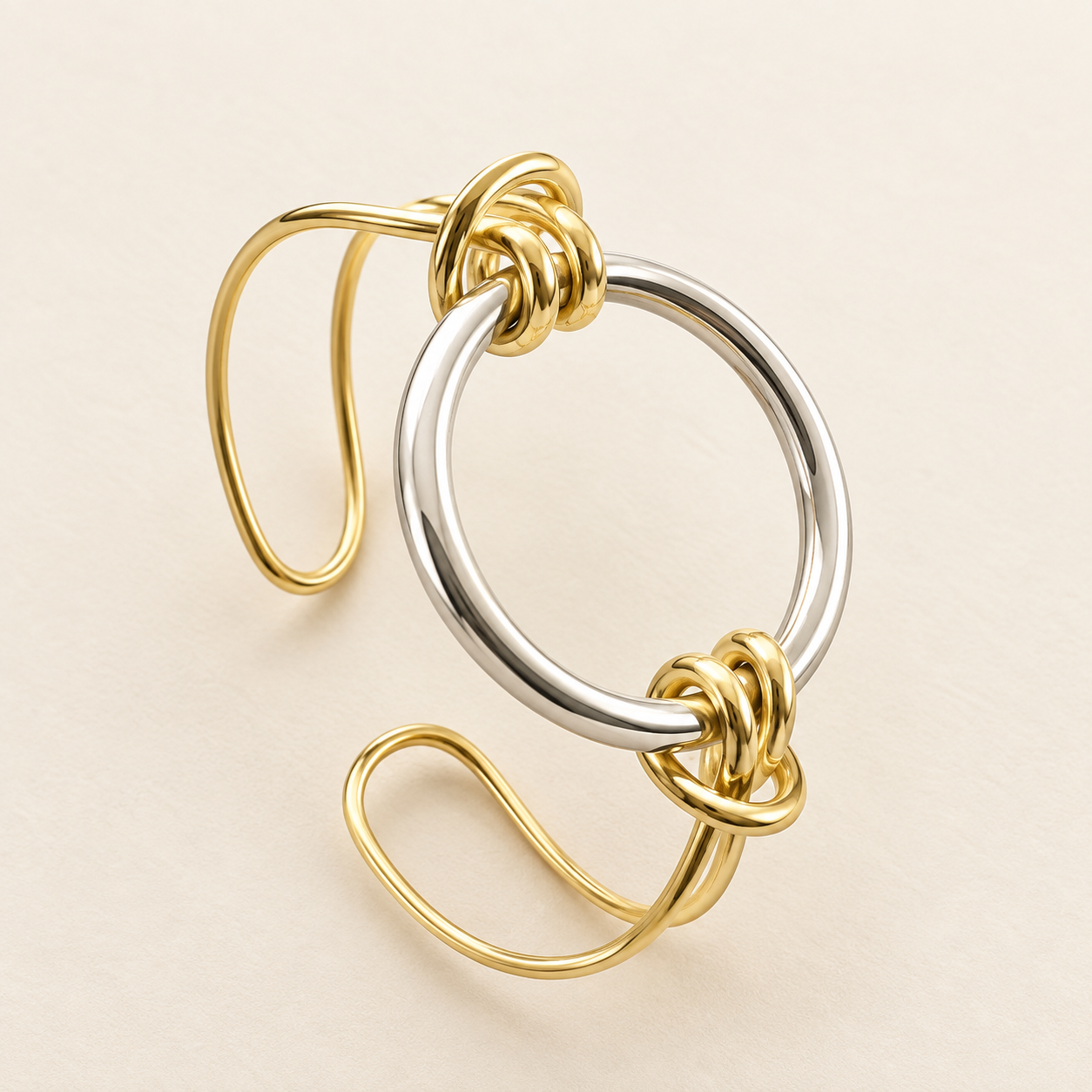 Gold and silver two-tone open kada bracelet with interlocking twisted knot design on a cream background