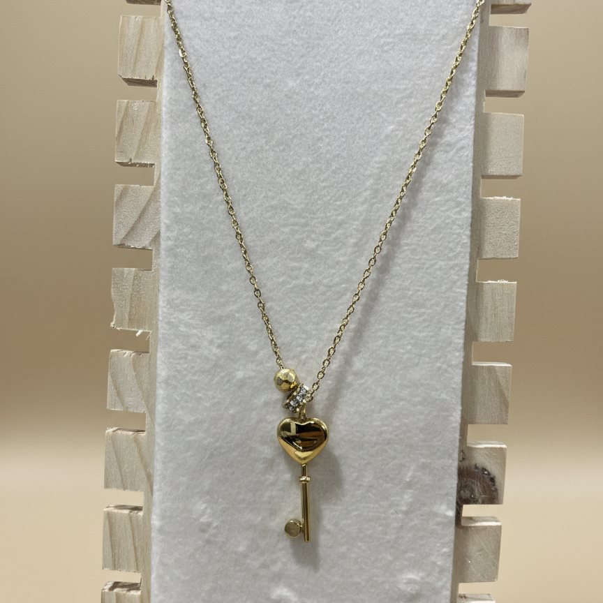 Polished gold heart key necklace for women displayed vertically on a professional wooden jewelry stand