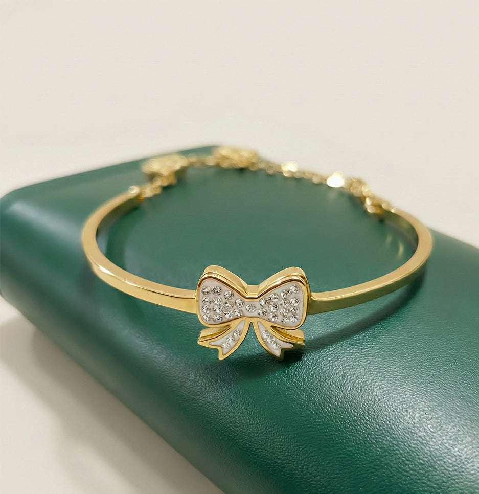 Full view of an anti-tarnish gold bangle with three hanging heart charms engraved with the word Love