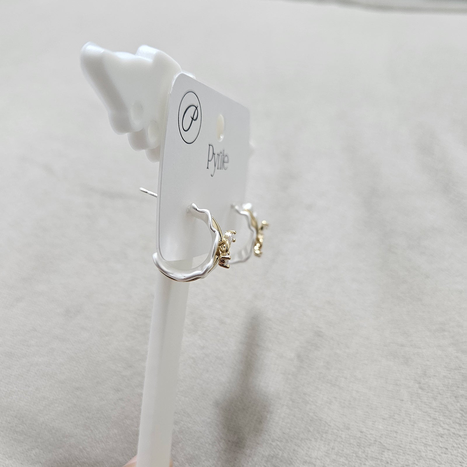 Pair of hoop earrings on a white card with 'zwelzy' branding against a light gray background