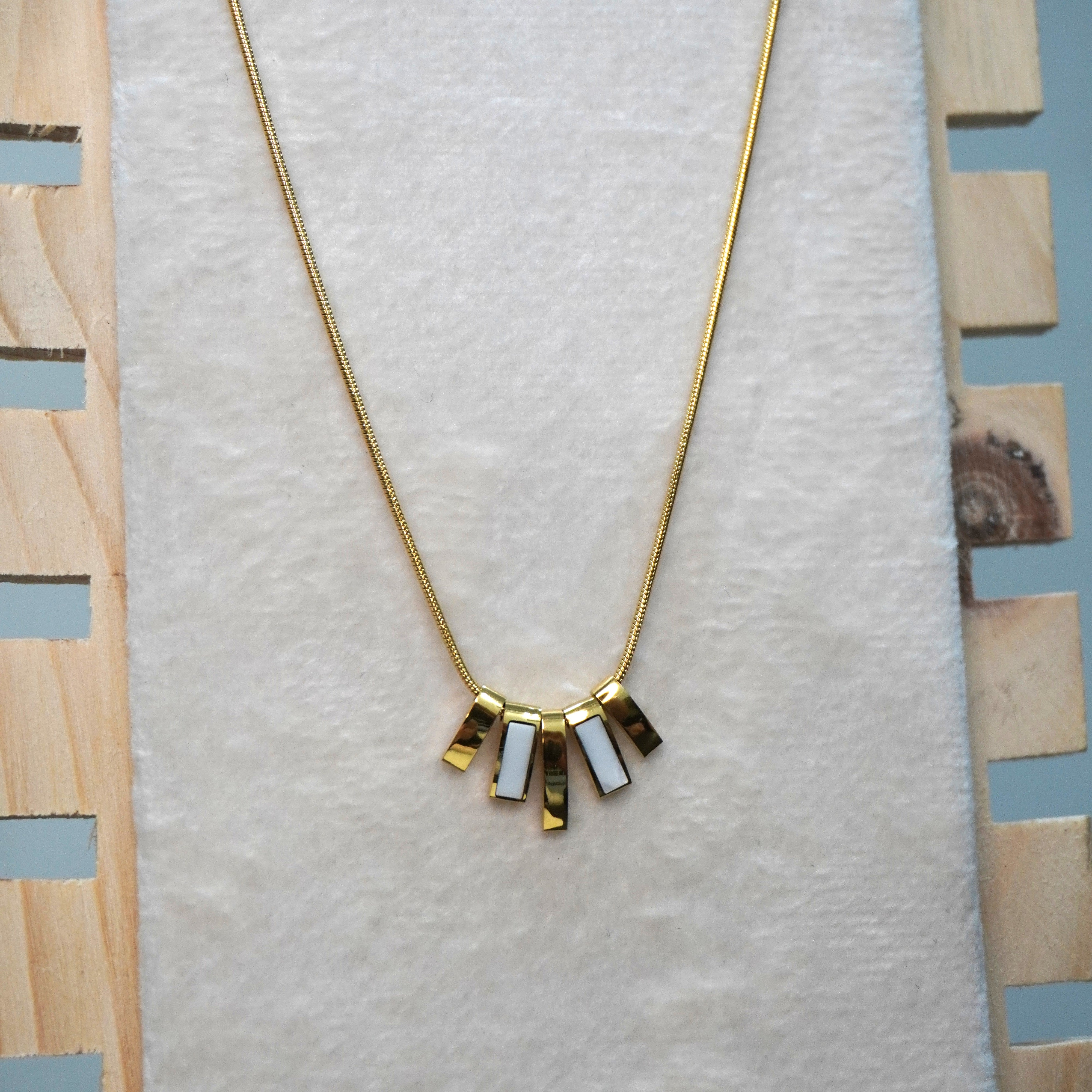 Gold necklace with pendant on a textured white surface