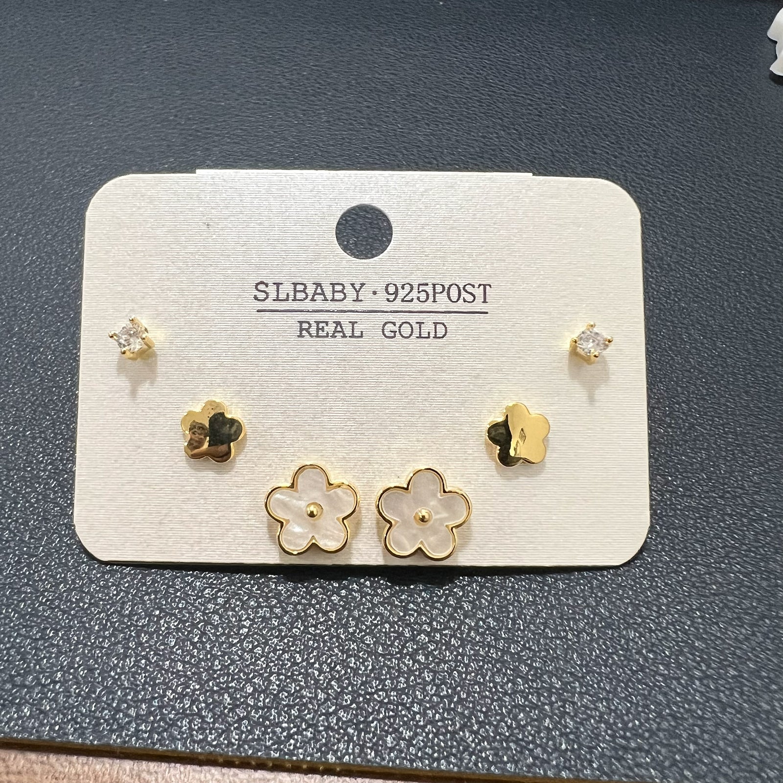 Angled view of a three-pair earring collection in anti-tarnish gold finish with white floral inlays and crystals.