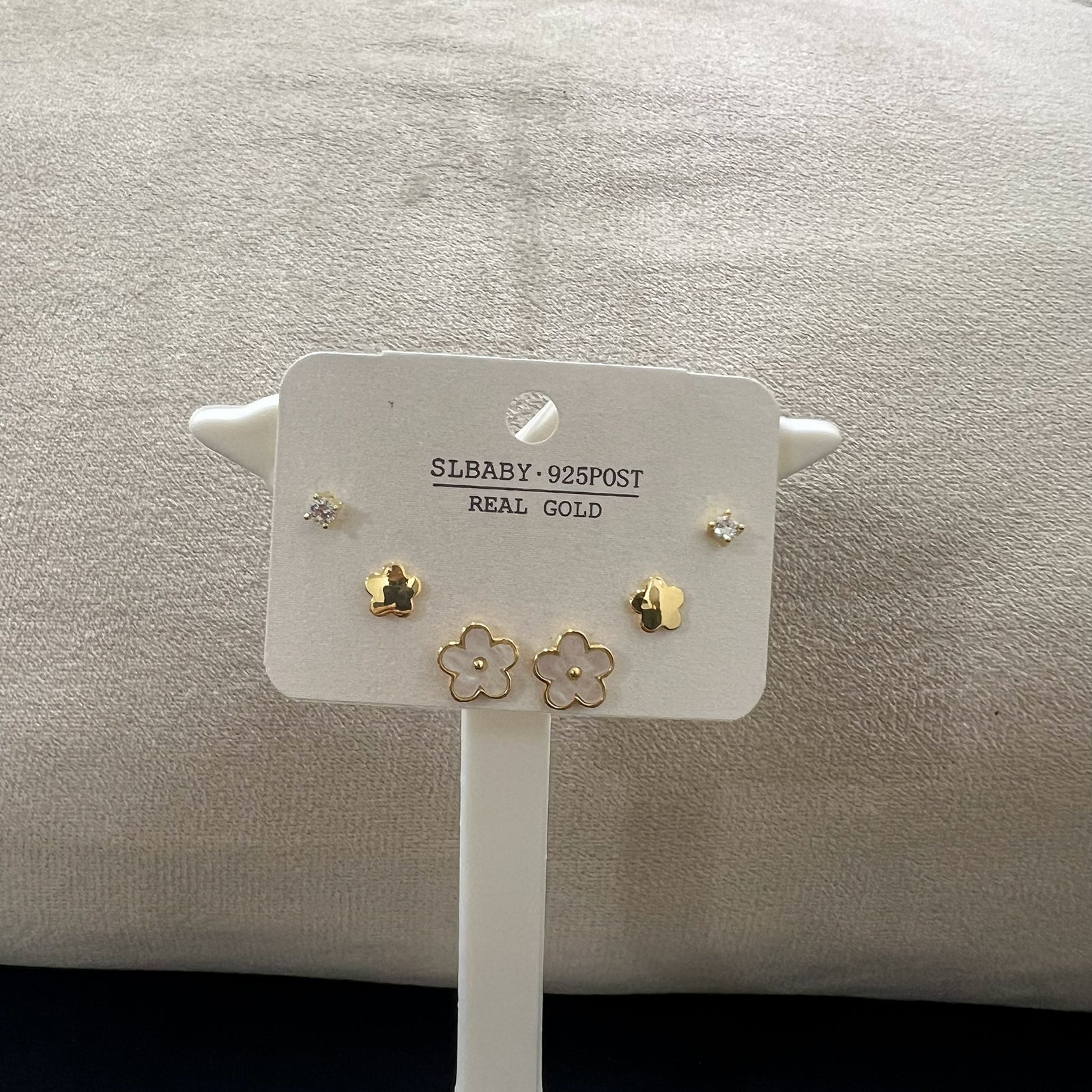 Angled view of a three-pair earring collection in anti-tarnish gold finish with white floral inlays and crystals.