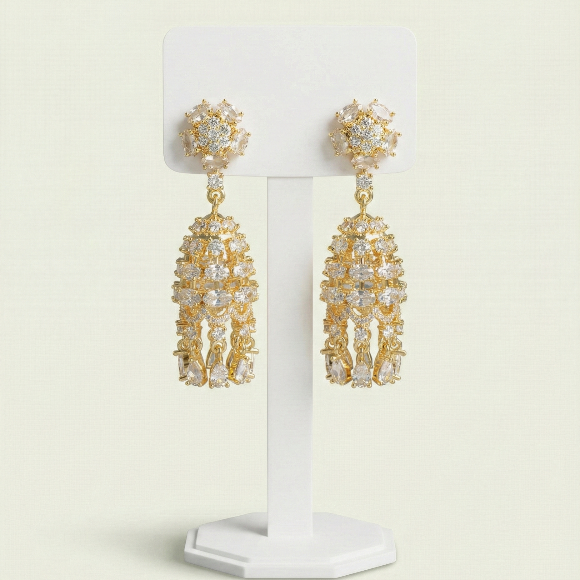 Front view of gold plated anti-tarnish jhumka earrings featuring sparkling marquise cut crystals on a white stand.