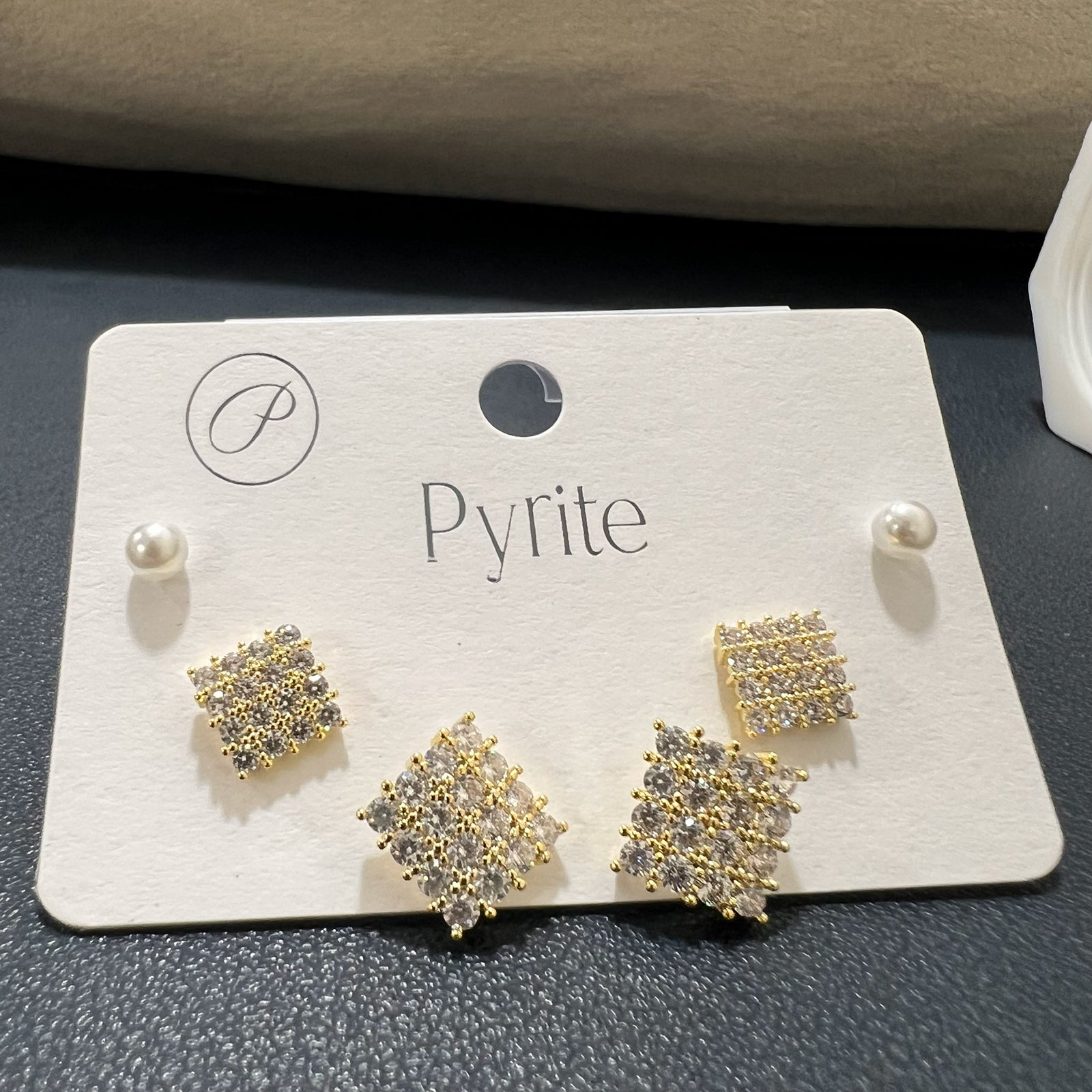 Close-up angled view of shimmering crystal-studded geometric earrings in an anti-tarnish gold finish