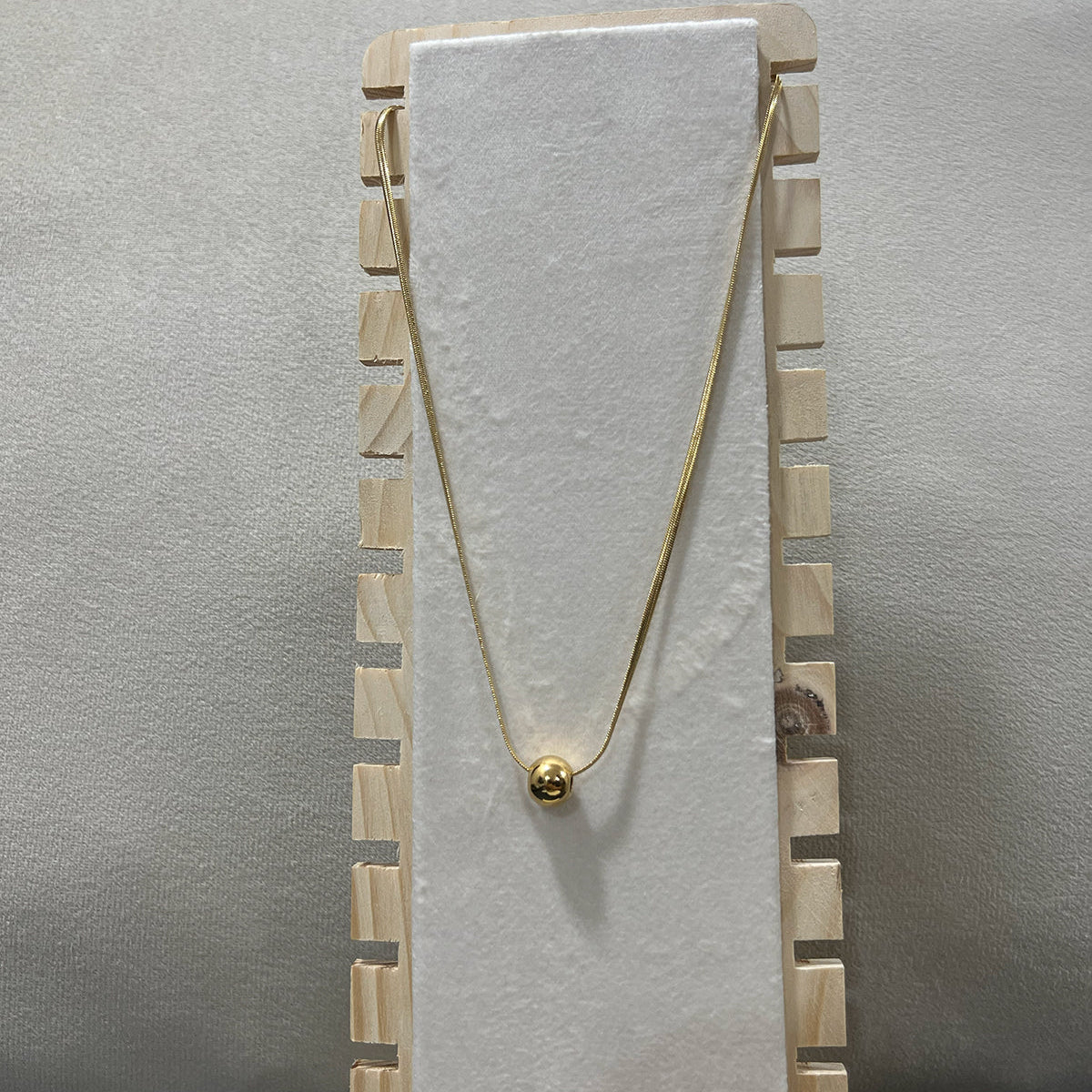 Close-up of a high-shine gold toned ball necklace in stainless steel highlighting the polished spherical charm - zwelzy designs