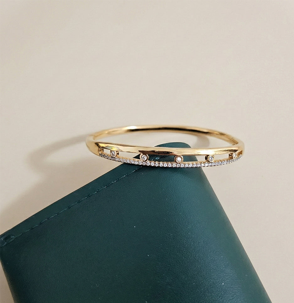 Premium gold-finish stone-studded bangle resting on a green leather prop for a professional lifestyle shot