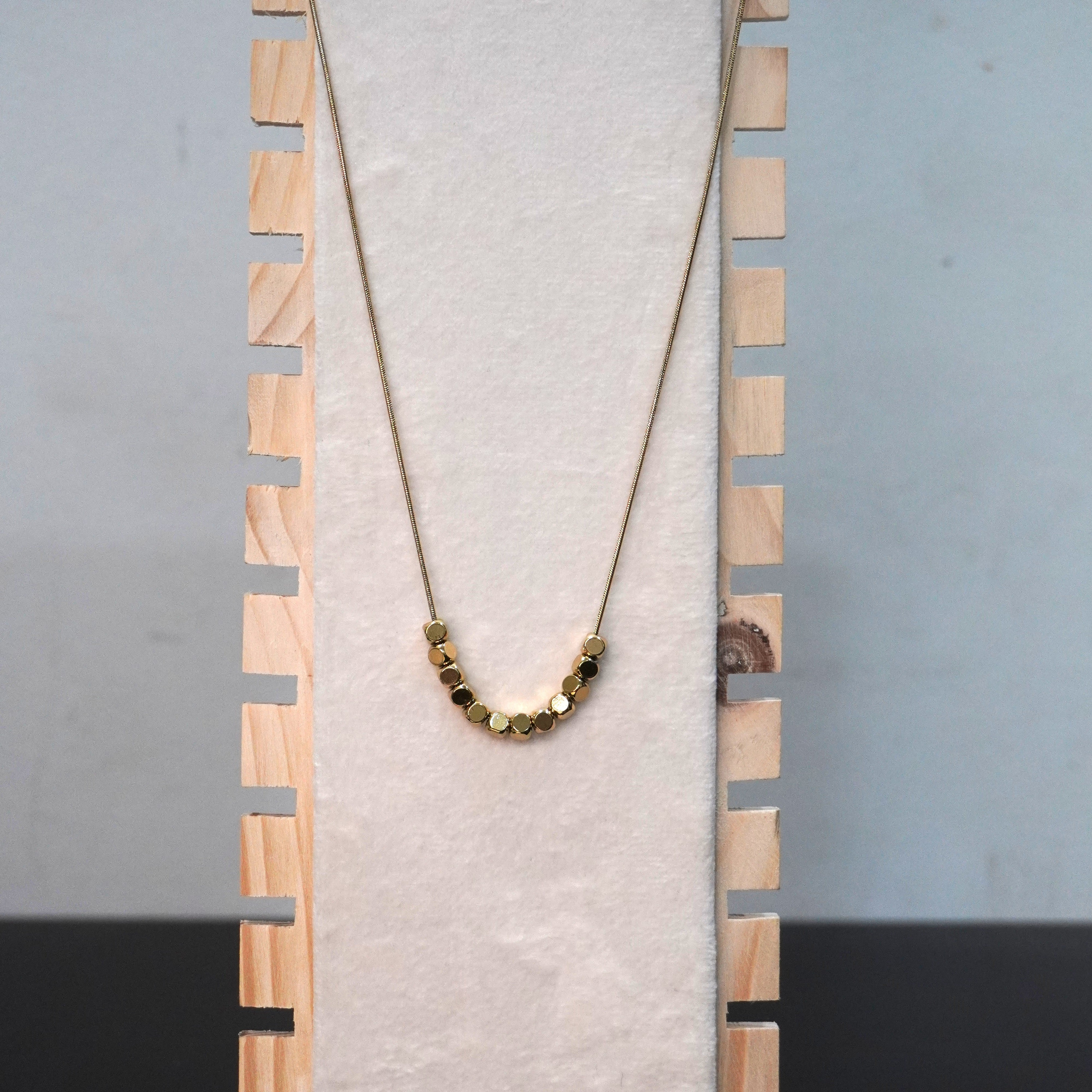 Necklace with beads on a wooden stand against a gray background