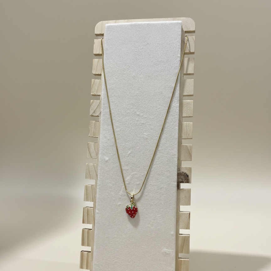A dainty gold plated strawberry charm necklace showcased on a professional wooden jewellery display stand.