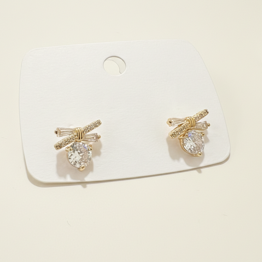 Exquisite gold plated bow stud earrings featuring a brilliant round center stone on a white display card