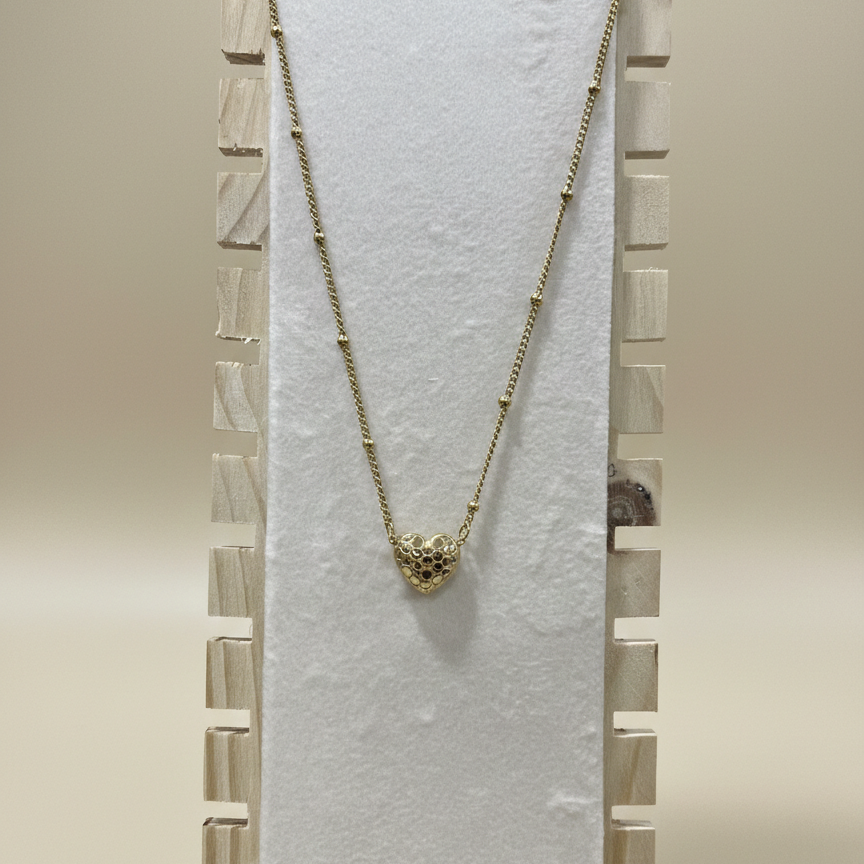 Premium anti-tarnish textured heart necklace in gold-toned stainless steel draped over a professional jewelry display stand.